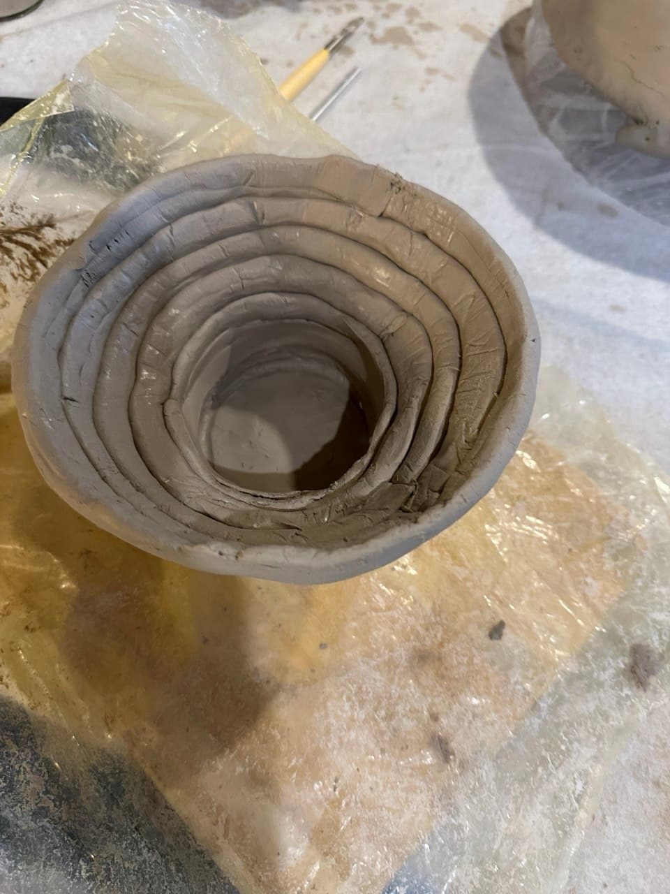 Un cuenco en construcción con la técnica de chorizos: rollos de arcilla cruda superpuestos en espiral