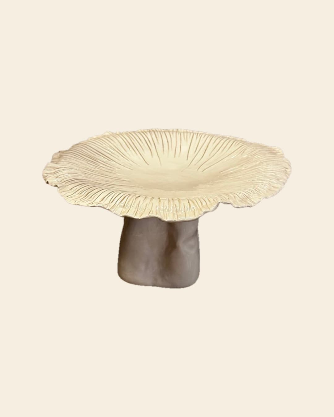 Hongo gigante de cerámica hecho a mano, de sombrero crema con laminillas marcadas y pie gris, sobre fondo beige