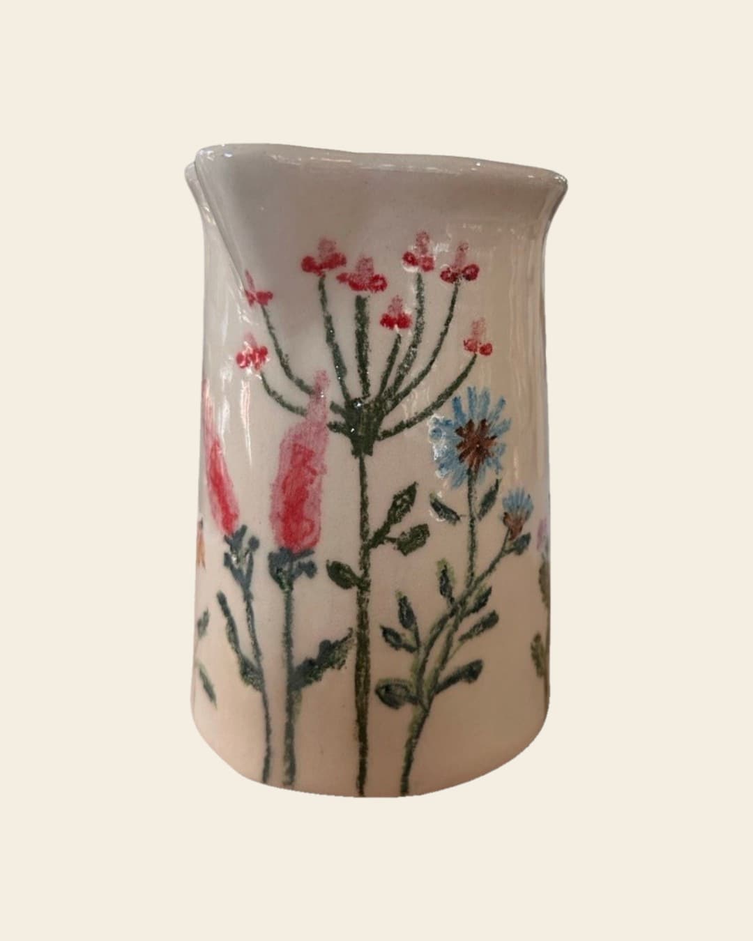 Jarra de cerámica color crema pintada a mano con flores silvestres de tallos finos en rojo, rosa y celeste